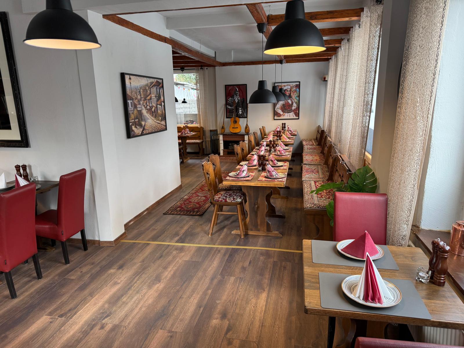 Der Gastraum des Troja Restaurants mit warmer Beleuchtung und roten Stühlen